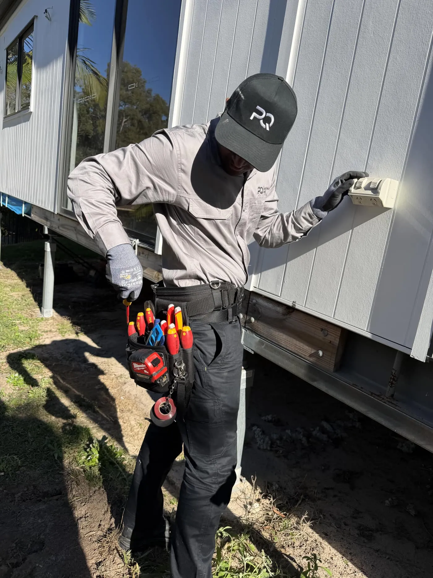 PQ Electrical & Air electrician in uniform and PQ cap installing an outdoor power point